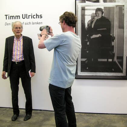 Timm Ulrichs in seiner Ausstellung Den Blitz auf sich lenken in der Galerie Wentrup, 11.6.2010 wird von dem Berliner Fotografen Jan Sobottka portraitiert. Rechts ein Foto von der Selbstausstellung als Erstes lebendes Kunstwerk bei der Juryfreien Kunstausstellung, 1965 in Berlin, obgleich er dort letztlich nicht zugelassen also ausjuriert wurde.