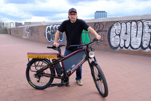 Bilder des Jahres 2021, Entertainment 08 August Entertainment Themen der Woche KW31 Entertainment Bilder des Tages Der Schauspieler Bjarne Maedel (Mädel, Botschafter des Projekts African E-Bikes ) auf dem E-Bike fuer Afrika in Hamburg (Foto vom 06.08.2021). In Kooperation mit Fahrradexperten aus Uganda, den deutschen Entwicklern der Firma HNF-Nicolai sowie dem indischen Hersteller HERO wurde ein spezielles, auf die afrikanischen Beduerfnisse abgestimmtes E-Bike produziert. 100 E-Bikes sollen im Oktober an die Partnerorganisation FABIO (First African Bicycle Information Organization) in Jinja Uganda uebergeben werden. (Siehe epd-Meldung vom 06.08.2021) E-Bike fuer Afrika