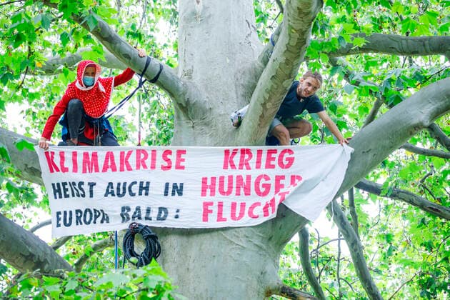 Bilder des Jahres 2021, News 08 August News Themen der Woche KW33 News Bilder des Tages Klima-Aktivisten besetzen Monbijou-Park Deutschland, Berlin am 16.08.2021: Zwei Klimaaktivisten mit Kletterseil hoch auf einem Baum. Sie zeigen ein Banner Klimakriese heisst auch in Europa bald: Krieg Hunger Flucht .