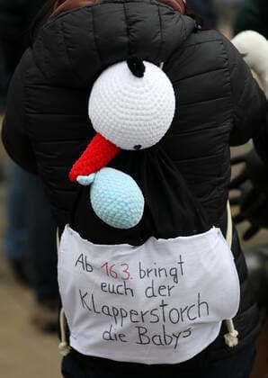 Erfurt - Grossdemo gegen die Impfpflicht 29.01.2022, Erfurt, Thueringer Staatskanzlei, Grossdemo unter dem Motto Gemeinsam gegen die Impfpflicht u.a. demonstriert das Pflegepersonal gegen die fuer den 15.03.2022 beschlossene Impfpflicht fuer Pflegekraefte im Bild: Hebamme mit Storch auf dem Ruecken und einem Rucksack mit der Aufschrift Ab 16.03. bringt euch der Klapperstorch die Babys