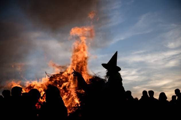 Bilder des Jahres 2023, News 04 April News Themen der Woche KW17 30.04.2023 Weimarer Land - Bergern: Ein Mädchen als Hexe verkleidet mit einem Hexenhut zeichnet sich als Silhouette vor einem traditionellen Feuer zur Walpurgisnacht ab.