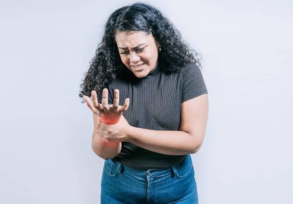Junge Frau mit Arthritis isoliert. Handgelenk Schmerzen und Arthritis Konzept. Menschen mit Schmerzen im Handgelenk und Arthritis isoliert