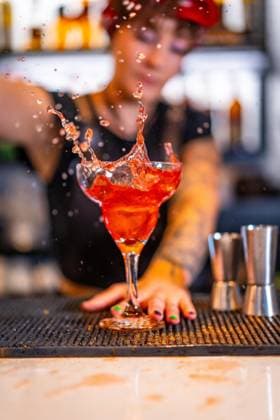 Vertikales Foto eines professionellen Barkeepers bei der Zubereitung eines Sex on the beach Cocktails