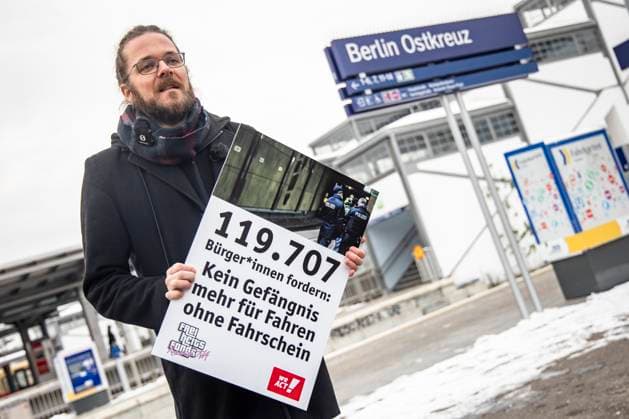 Organisator Arne Semsrott mit einem Plakat vor der Protestlesung gegen die Kriminalisierung des Fahrens ohne Ticket am Ostkreuz in Berlin am 5. Dezember 2023. Protestlesung gegen die Kriminalisierung des Fahrens ohne Ticket