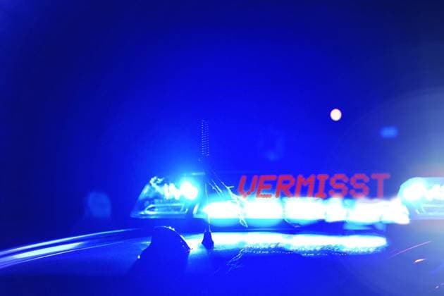 Streifenwagen der Polizei bei Nacht, mit der Blaulicht Aufschrift: Vermisst. Symbolbild für Personenfahndung und Nahbereichsfahndung. FOTOMONTAGE
