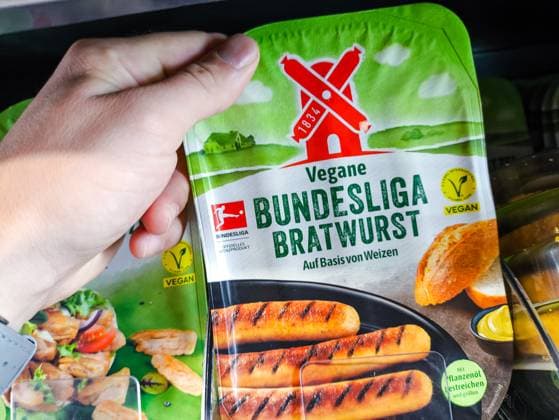 Kunde hält eine Packung vegane Bundesliga Bratwurst von der Marke Rügenwalder Mühle in der Hand. Fleischersatzprodukt