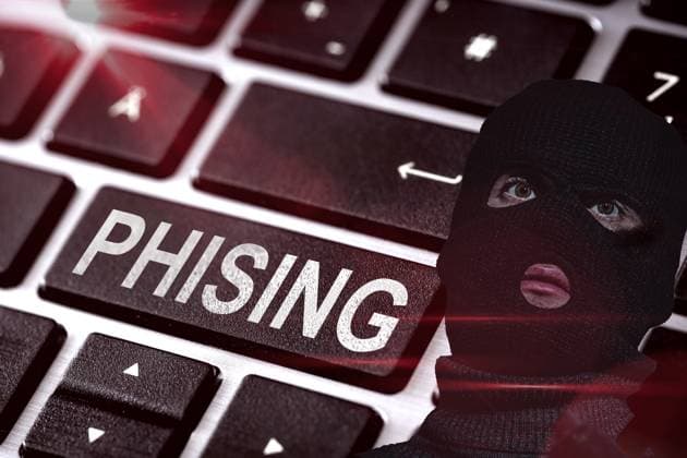 Tastatur eines Computers, bzw. Laptops, neben einer maskierten Person mit schwarzer Räuber-Maske. Konzept Phishing online im Internet - gefälschte Webseiten, E-Mails oder Fake Kurznachrichten per WhatsApp. FOTOMONTAGE