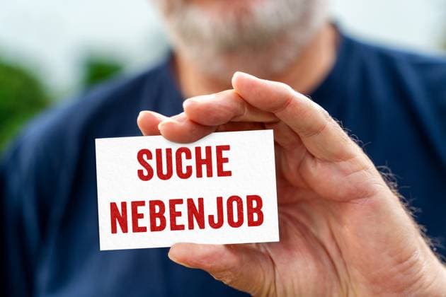 Alter Mann hält ein Schild mit Aufschrift: Suche Nebenjob. FOTOMONTAGE