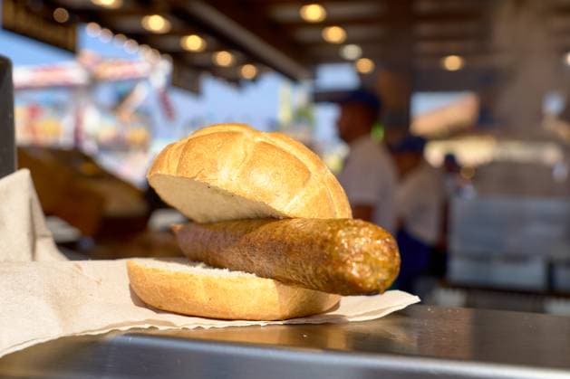 Vegane Bratwurst im Brötchen auf dem Oktoberfest zu sehen bei einem der zahlreichen Imbissstände. Die vegane Wurst wird traditionell im Semmel serviert und bietet eine pflanzliche Alternative zu den sonst fleischlastigen Spezialitäten des Festes