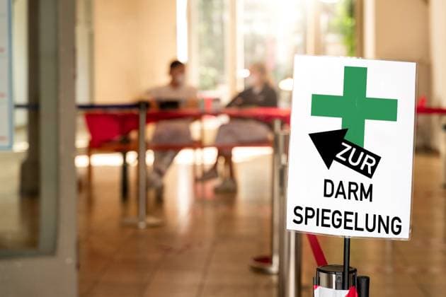 Zur Darmspiegelung! Steht auf einem Schild, einer Arztpraxis, bzw. in einer Praxis für Gastroenterologie. Zu sehen sind medizinische Fachangestellte. Symbolisiert Durchführung einer Koloskopie, um eventuell vorhandene Polypen zu entdecken und zu entfernen, welche Vorstufen von Darmkrebs sein können. FOTOMONTAGE