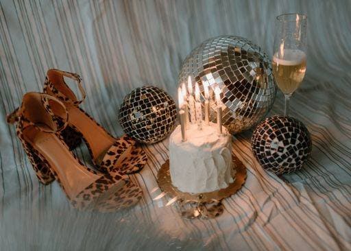 A festive setup with a cake, candles, disco balls, leopard print shoes, and champagne 28818693 RECORD DATE NOT STATED
