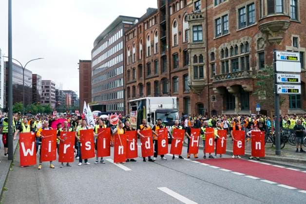 HAMBURG-Demonstration der Hafenarbeiter Mit Verd.i Fahnen Banner Transparenten mit der Aufschrift Wir sind der Hafen Hunderte fordern mehr Lohn und bessere Arbeitsbedingungen Die Demonstration führte zu massiven Verkehrsbehinderungen in der Innenstadt Mehrere hundert Menschen nahmen an der Demonstration von Verdi für mehr Geld und bessere Arbeitsbedingungen für die Hafenarbeiter teil . Die Demonstration startete in der Hafencity, ging weiter über den Bereich der Innenstadt zum Gewerkschaftshaus am Besenbinderhof.am 10.07.2024 HH Deutschland