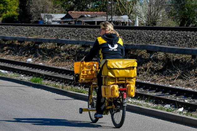 Deutschland, Baden-Wuerttemberg, Ebersbach an der Fils 05.04.2025, Deutschland, GER, Baden-Wuerttemberg, Ebersbach an der Fils, im Bild Themenbild, Deutsche Post, Postbotin, Brieftraeger, Fahrrad, Zustellung, Post, Briefe, Pakete, Paeckchen, DHL Baden-Wuerttemberg