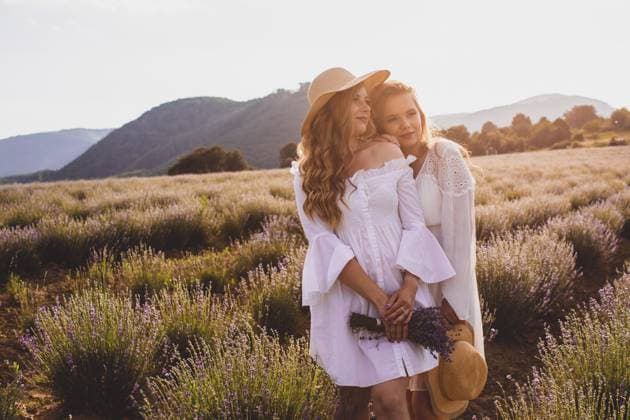 Sommerlicher Sonnenuntergang über zwei Freundinnen in weißen Kleidern, die eng beieinander in einem Lavendelfeld stehen und in den Hintergrund schauen. Verbringen Zeit zusammen nach langer Pause Summer sunset over two women friends in white dresses, standing close to each other in lavender field, looking away in back lit. Spending time together after long break Copyright: imageBROKER OksanaxShufrych ibxiqx13438358.jpg ,model released, Symbolfoto ,property released