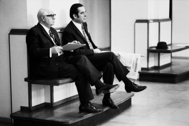Hamburg, Januar 1972 Zwei Herren in Anzug und Krawatte sitzen nebeneinander auf einer schlichten Holzbank am Rand des Börsensaals der Hamburger Wertpapierbörse. Der linke Mann ist weißhaarig, trägt eine Brille und hält ein Notizbuch oder Börsenverzeichnis in den Händen. Der jüngere Mann neben ihm mit zurückgekämmtem Haar hält eine Ausgabe der Wirtschaftszeitung Handelsblatt auf dem Schoß. Hamburg Hamburg Deutschland Copyright: xUnitedxArchivesx xSvenxSimonxArchives SVS_94010000629