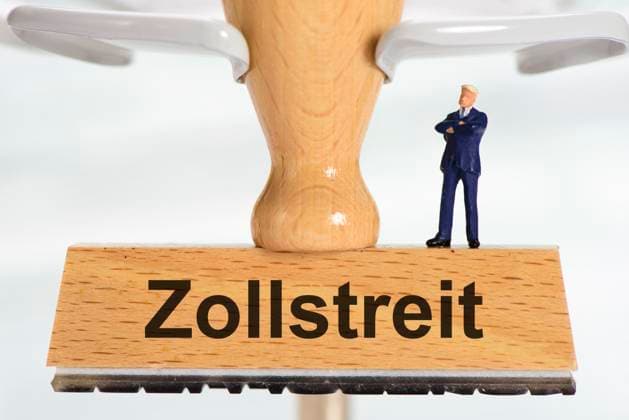 Zollstreit zwischen USA und EU Ein Holzstempel ist beschriftet mit dem Aufdruck Zollstreit, zwischen USA, Europa und Deutschland