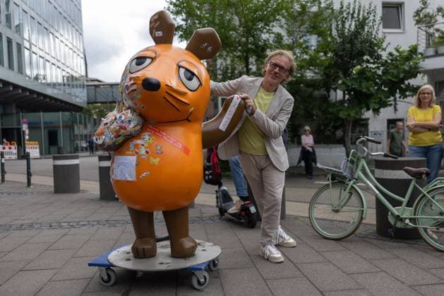 News Bilder des Tages Die WDR Maus geht in Kur - 01.08.2025 Leiter des WDR Kinderfernsehen Matthias KÖRNICH verabschiedet die Maus - Nach dem Brandanschlag wird das beschädigte Maus-Denkmal der Sendung mit der Maus vor dem WDR-Gebäude an der Mörsergasse in Köln in Kur geschickt. Ihre Brandstellen werden restauriert und möglichst bald wieder an ihren angestammten Platz zurück gebracht. Die angebrannte Skulptur ist mit Trostpflastern und mutmachenden Botschaften ihrer großen und kleinen Fans versehen. Deutschland Copyright: xBonn.digitalx