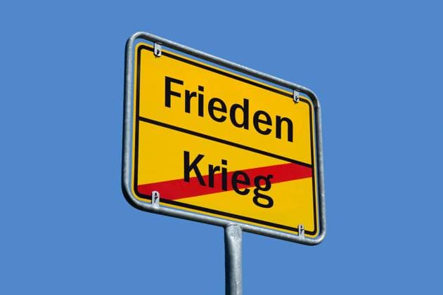 Ortsschild mit Schriftzügen Frieden und Krieg Fotomontage: Ortsschild mit Schriftzügen Frieden und Krieg, 22.08.2025, Auf einem Ortsschild stehen die Schriftzüge Frieden und Krieg.