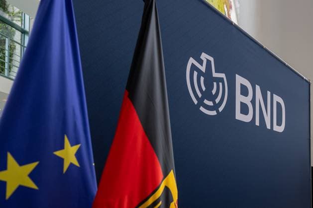 Tag der offenen Tür 2025 im Bundeskanzleramt, Berlin, 23.08.2025 Detailansicht des Informationsstands des Bundesnachrichtendienstes (BND) im Bundeskanzleramt in Berlin während des Tags der offenen Tür der Bundesregierung. Vor dem blauen Hintergrund mit BND-Logo stehen eine Deutschlandflagge und eine Europaflagge. Tiergarten Berlin Deutschland