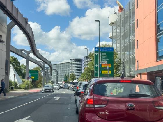 Düsseldorf, Nordrhein-Westfalen, Deutschland, Europa: Verkehrsszene am Flughafen Düsseldorf, Zufahrt zu Terminal und Parkhäusern, Wegweiser für Abflug, Ankunft, Mietwagen, Stau und Reiseverkehr, Flughafeninfrastruktur, SkyTrain-Trasse, moderne Architektur, Mobilität, Luftfahrt, Pendelverkehr, Infrastruktur Deutschland, Urlaubsreisen. Copyright: xJOERANxSTEINSIEKx