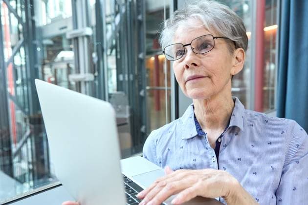 Eine erfahrene Seniorin arbeitet konzentriert am Laptop im Unternehmen. Das Bild zeigt, wie Aktivrente und Arbeiten bis 70 neue Chancen im Rentenalter ermöglichen.