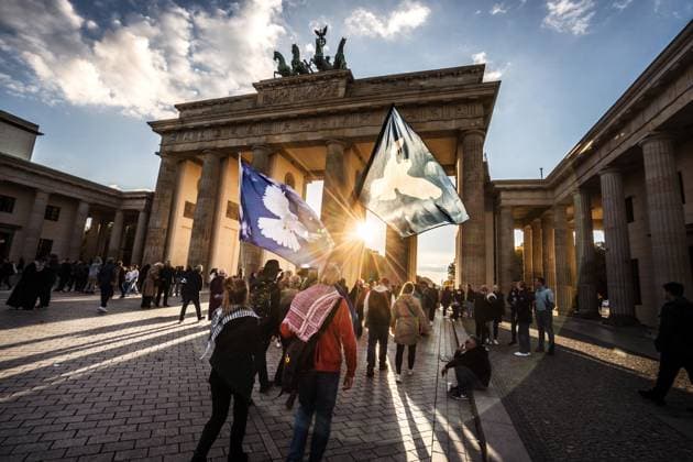 Tag der Deutschen Einheit, Friedensfahnen leuchten symbolisch in der Abendsonne am Brandenburger Tor, Berlin, 3. Oktober 2025 Deutschland, Berlin, 3. Oktober 2025, Tag der Deutschen Einheit, Friedensfahnen leuchten in der Abendsonne am Brandenburger Tor, Demonstrierende einer schon beendeten Pro-Gaza-Friedensdemo gehen über den Pariser Platz, Frieden, Politik,