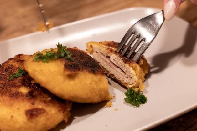 Veganes Cordon Bleu angerichtet Symbol für EU-Streit um Produktbezeichnungen 25.10.25, Selters: Symbolfoto, Illustrationsbild, Symbolbild, Illustrationsfoto, Alltagsszene Eine Person schneidet ein veganes Cordon Bleu auf, das auf einem Teller serviert ist. Das pflanzliche Fleischersatzprodukt zeigt den typischen Schichtenaufbau eines klassischen Cordon Bleu. Das Foto steht im Kontext der EU-Debatte über die Verwendung traditioneller Fleischbezeichnungen für vegane und vegetarische Alternativen. Aufnahme in Deutschland, 2025. Selters Hessen Deutschland Copyright: xThorstenxWagnerx