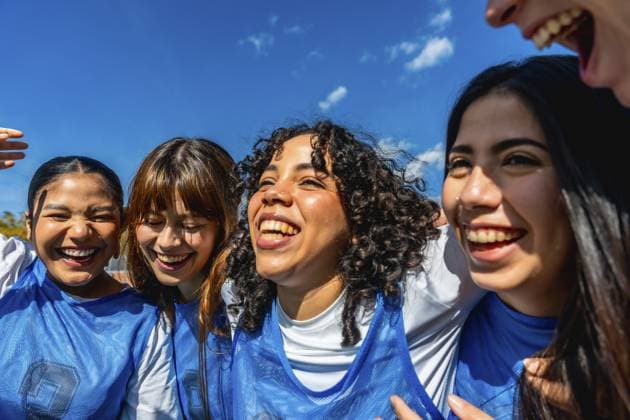 Vielfältige Gruppe junger Mädchen, die unter strahlend blauem Himmel in der Nähe stehen, lächeln und lachen, Teamgeist verkörpern und nach einem Sportspiel starke Freundschaft und Kameradschaft pflegen Diverse group of young girls standing close, smiling and laughing under a bright blue sky, embodying team spirit and fostering strong bonds of friendship and camaraderie after a sports game Copyright: imageBROKER UnaixHuizi ibxuhu15580068.jpg ,model released, Symbolfoto ,property released