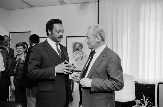Der US-amerikanische Bürgerrechtler Jesse Jackson und der SPD-Ehrenvorsitzende Willy Brandt im Gespräch am 9. Mai 1985 in Bonn. Die Aufnahme zeigt beide Politiker in angeregtem Austausch in einem Büroraum, umgeben von Begleitpersonen und Presse. Im Hintergrund ein Porträt von Friedrich Engels. Bonn Nordrhein-Westfalen Deutschland Copyright: xUnitedxArchivesx xSvenxSimonxArchives SVS_94010001489