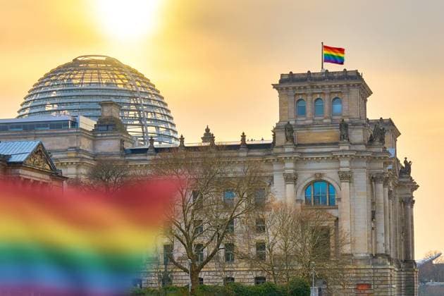 FOTOMONTAGE, Vor dem Deutschen Bundestag weht eine Regenbogenflagge und steht symbolisch für LGBTQ-Rechte, Vielfalt und Gleichberechtigung. Das Bild verbindet politische Debatten mit dem Einsatz für Akzeptanz und gesellschaftliche Offenheit.