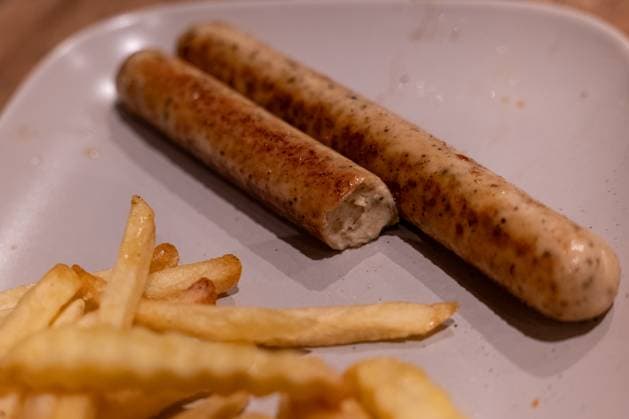 Vegane Bratwürste mit Pommes auf Teller 16.11.25, Selters: Symbolfoto, Illustrationsbild, Symbolbild, Illustrationsfoto, Alltagsszene Auf einem Teller liegen zwei gebratene vegane Bratwürste, von denen eine bereits angebissen ist. Im Vordergrund befinden sich Pommes frites. Das Foto zeigt eine servierte, einfache Mahlzeit mit pflanzlichem Fleischersatz und Beilage. Selters im Taunus Hessen Deutschland Copyright: xThorstenxWagnerx