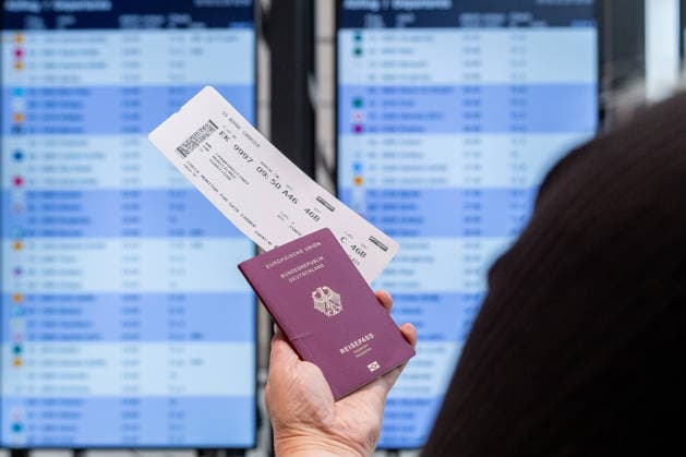 Eine Reisende hält ihr Flugticket vor der Abflugtafel im Flughafen. Die Szene zeigt typische Abläufe einer Flugreise von der Kontrolle der Fluginformationen bis zur Vorbereitung des Boardings. Am Tag des Probebetriebs für den neuen Flugsteig im Terminal 1 des Flughafens München.