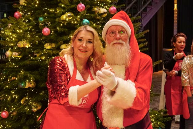 CNTVhamburg: Sandra Quadflieg Schauspielerin mit dem Weihnachtsmann John Langley NDR Gaertner als Promi Helfer bei der Weihnachtsfeier fuer Obdachlose Menschen unter dem Motto Mehr als eine warme Mahlzeit in der Fischauktionshalle am 02.12.2025 in Hamburg Hamburg Deutschland