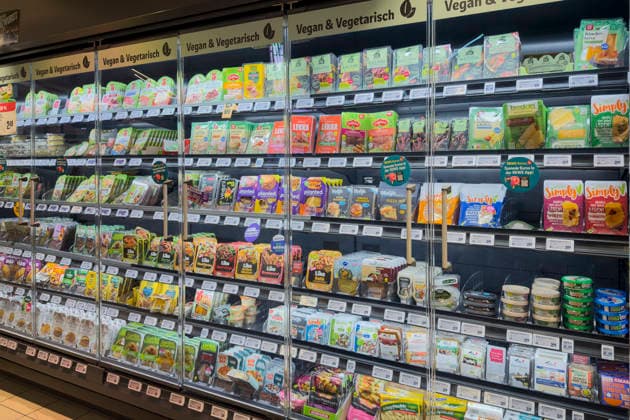 Kühlvitrine mit veganen und vegetarischen Produkten in einer REWE-Filiale in Köln. Ein breites Sortiment an pflanzlichen Alternativen, das den wachsenden Trend zu bewusster Ernährung widerspiegelt.