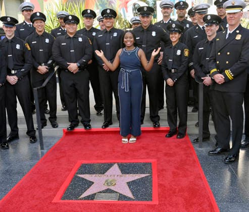 Eniola Taiwo (C) participates in an unveiling ceremony honoring the Los Angeles Fire Department with an Award of Excellence star adjacent to the Hollywood Walk of Fame in Los Angeles on Tuesday, December 2, 2025. Taiwo, 14, wrote a letter to the Hollywood Chamber of Commerce suggesting that firefighters who battled the deadly January fires were worthy of a star on the Hollywood Walk of Fame. The letter precipitated the tribute.  LAP2025121211 JIMxRUYMEN