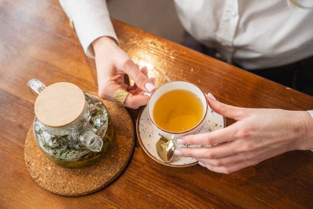 Woman holding cup of tea. Cozy cafe setting. Top view. Orenburg, Orenburg Oblast, Russia R_LQBD251210-1906489-01
