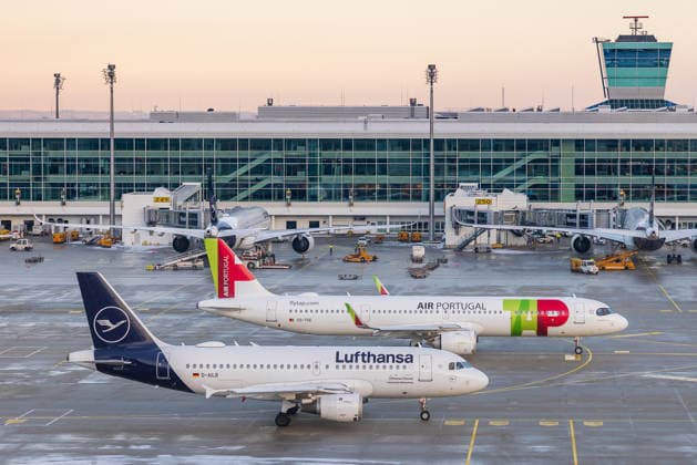 Flughafen München im Schneebetrieb während Kältewelle in Bayern, Oberding, 11.01.2026 Zwei Flugzeuge der Lufthansa und TAP Air Portugal stehen am Terminal des Flughafens München. Die Aufnahme zeigt Maschinen beider Airlines in direkter Nachbarschaft ein visuelles Symbol für die strategische Nähe der Fluggesellschaften im Rahmen von Übernahmeinteressen durch die Lufthansa Group. Oberding Flughafen München Bayern Deutschland