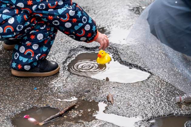 Rosenmontagszug in Düsseldorf, Teilnehmer des Umzugs, Kind spielt mit Plastikentchen, das es beim Zug als Kamelle gefangen hat, machen sich regenfest, beim Strassenkarneval, bei teils starkem Regen, NRW, Deutschland Rosenmontag DUS