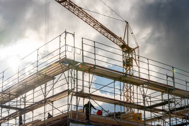 Eine düstere Baustelle vor Gewitterwolken mit Baukran und Gerüst zeigt den Bau neuer Gebäude. Wohnungsbau und Bauprojekte stehen häufig im Fokus politischer Diskussionen über Wohnraummangel, Baupolitik, Bauturbo Programme und Arbeitsplätze in der Bauwirtschaft.
