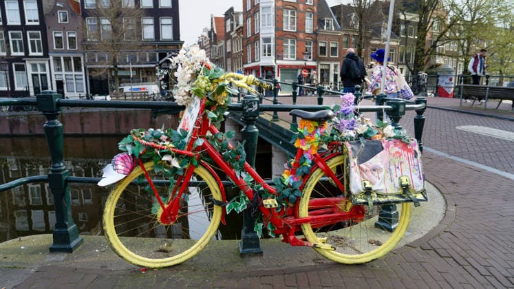 Kunst Malerei Architektur Tourismus 22.-26.03.2026 Amsterdam Niederlande Holland Prinsengracht Die Blumenfahrräder in Amsterdam sind eine bekannte Kunstinstallation und ein beliebtes Fotomotiv, oft entlang der Grachten zu finden. Initiiert von Warren Gregory, dem Flower Bike Man, wurden über 300 bunte, künstliche Blumenarrangements auf Fahrrädern in der Stadt verteilt, um Freude zu verbreiten und als Liebeserklärung an seine Frau. Foto Eberhard Thonfeld Amsterdam NED