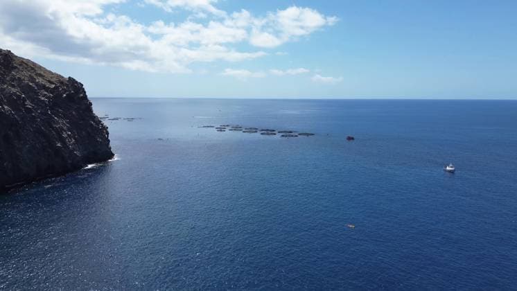 Küstenlinie des Atlantic Ocean mit Fischfarmen und einem Boot an einem sonnigen Tag