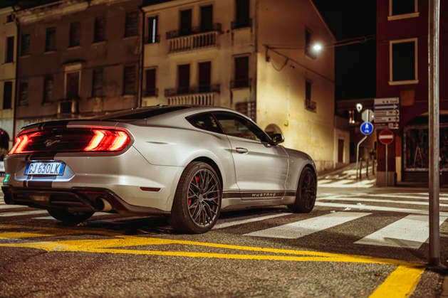 Vo, italy 28 october 2025: silver ford mustang muscle car parked on city street at night, sleek urban lifestyle shot with lit buildings and wet asphalt reflections Ford mustang parked on urban crosswalk at night Copyright: xFilippoxCarlotx giro (314)