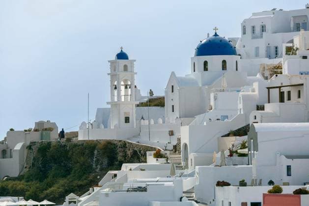 White church with blue dome and bell tower at sunset in Fira village on Santorini island in Greece Copyright: xkavalenkavax Panthermedia100656148.jpg