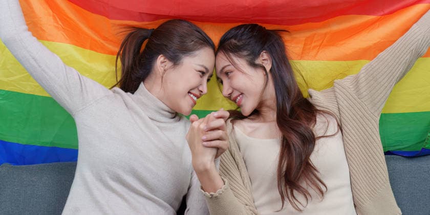Ein asiatisches lesbisches Paar, das Händchen hält ? ein inniger Moment vor einer Regenbogenfahne An Asian lesbian couple shares a tender, intimate moment, holding hands and looking into each other s eyes, with a vibrant rainbow pride flag behind them. This image conveys love, connection, and LGBTQ pride. (License=RF) ,model released, Symbolfoto Copyright: xZoonar.com WORAWEExMEEPIANx 24992716 ,model released, Symbolfoto ,property released