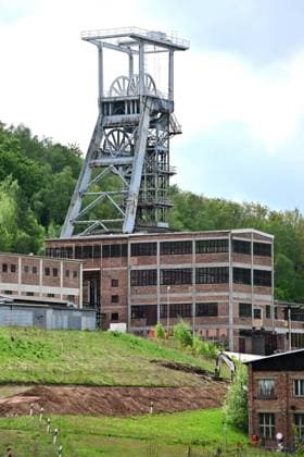 Neue Aussichtsplattform am Schacht 371 eröffnet Wismut macht Bergbaugeschichte erlebbar Neue Aussichtsplattform am Schacht 371 eröffnet Wismut macht Bergbaugeschichte erlebbar Die Wismut GmbH hat heute am traditionsreichen Schacht 371 bei Hartenstein eine neue Aussichtsplattform eröffnet und damit einen weiteren öffentlich zugänglichen Ort geschaffen, an dem die Geschichte des Uranerzbergbaus im Westerzgebirge sichtbar und erfahrbar wird. Im Bild: Blick auf die Übertageanlagenmit dem Fördergerüst. Der Standort zählt zu den bedeutendsten Anlagen des ehemaligen SDAG Wismut Bergbaus. Der Schacht war bis zu seiner Stilllegung 1991 das tiefste Bergwerk Deutschlands. Die neue Plattform bietet einen freien Blick auf Aue-Bad-Schlema_Wismut_032-0605-26