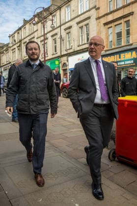 First Minister of Scotland John Swinney joins SNP candidate Alex Kerr campaigning in Hamilton - 06 May 2026 First Minister of Scotland John Swinney (right) and SNP candidate Alex Kerr (left) walk together through the constituency. The day before the Scottish parliamentary elections, First Minister of Scotland John Swinney visits Hamilton in South Lanarkshire, the constituency of SNP candidate Alex Kerr to kick off the final day of campaigning by meeting potential voters and owners of local businesses. Hamilton United Kingdom Copyright: xNeilxMiltonx xSOPAxImagesx L1000764