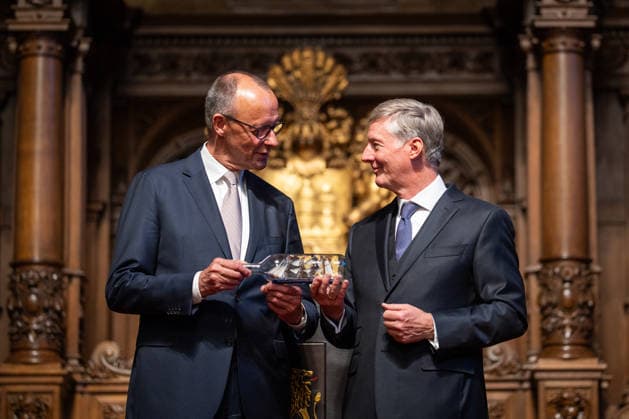 Friedrich Merz, Bundeskanzler, nach seiner Festrede im Hamburger Rathaus, mit Harald Vogelsang, Präsident Übersee-Club und Vorstandsvorsitzender Hamburger Sparkasse bei der Übergabe eines Buddelschiffs als traditionelles Gastgeschenk;76. Großer Übersee-Tag in Hamburg, April 2026 Festakt im Hamburger Rathaus, Hamburg Hamburg Deutschland Rathaus