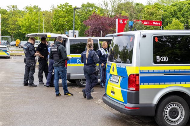 Großer Polizeieinsatz im Bereich Ulrich-Schwarz-Straße in Augsburg Pfersee. Mehrere Polizeikräfte koordinieren den laufenden Einsatz neben Einsatzfahrzeugen vor Ort.