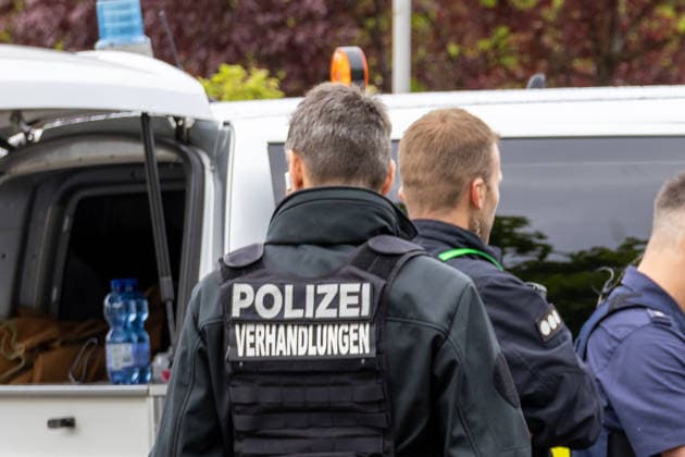 Großer Polizeieinsatz im Bereich Ulrich-Schwarz-Straße in Augsburg Pfersee. Ein Polizeiverhandler steht während des laufenden Einsatzes mit weiteren Kräften am Einsatzort.