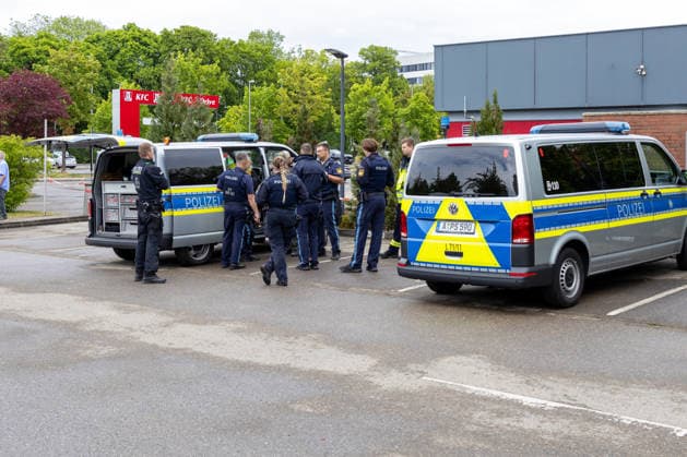 Großer Polizeieinsatz im Bereich Ulrich-Schwarz-Straße in Augsburg Pfersee. Mehrere Polizeikräfte koordinieren den laufenden Einsatz neben Einsatzfahrzeugen vor Ort.